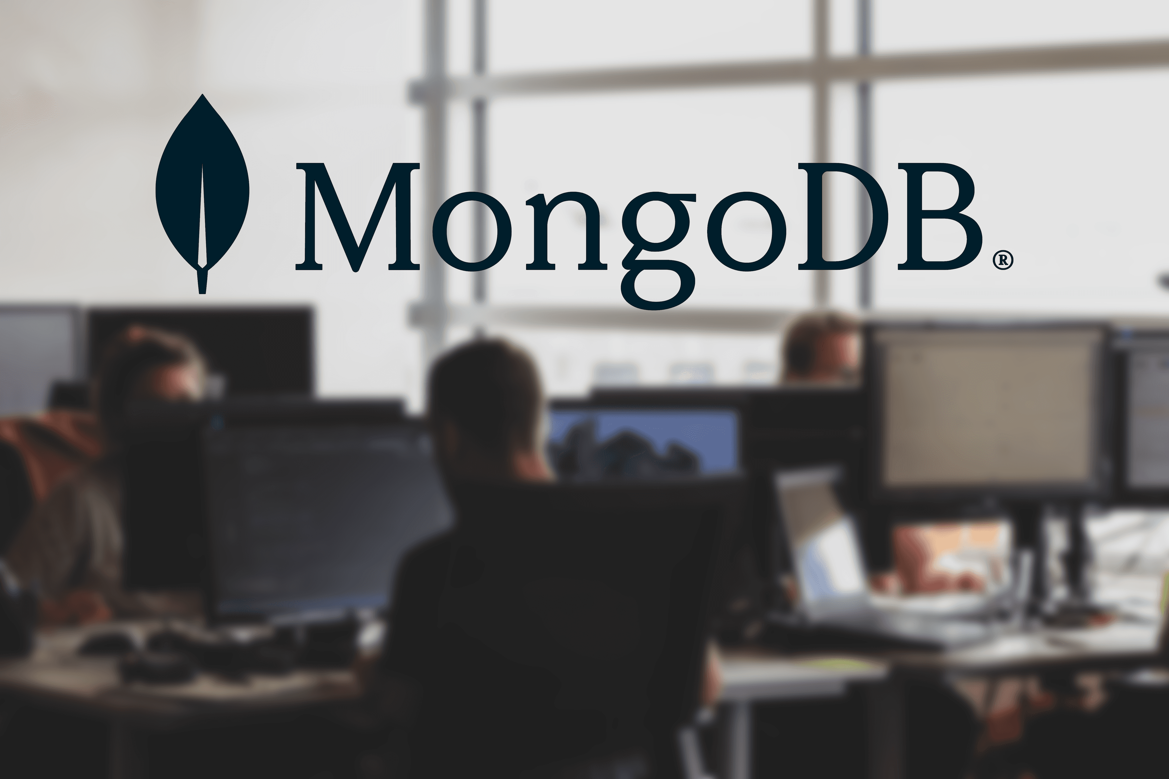 Developers working on computers with MongoDB logo in the foreground