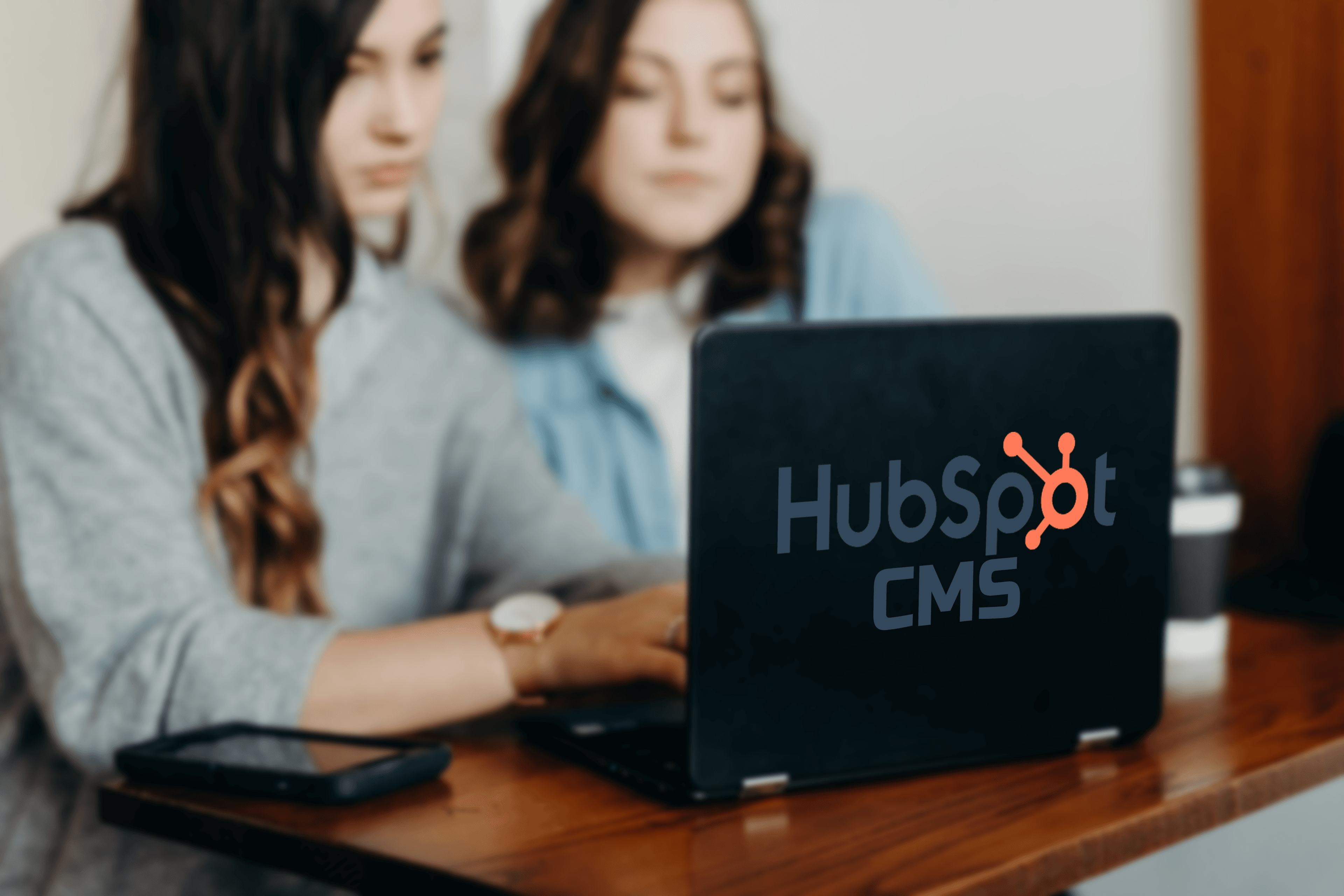 Women using laptop with HubSpot CMS logo in the front